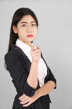 Asian woman in suit looking at camera and pointing finger on gray background
