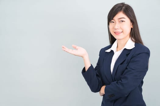 Asian woman in suit open hand palm gestures with empty space isolated on gray background