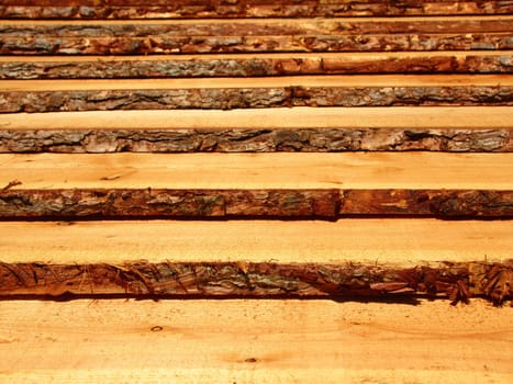 Rough wooden pine planks with bark on the side. It resembles a set of stairs.