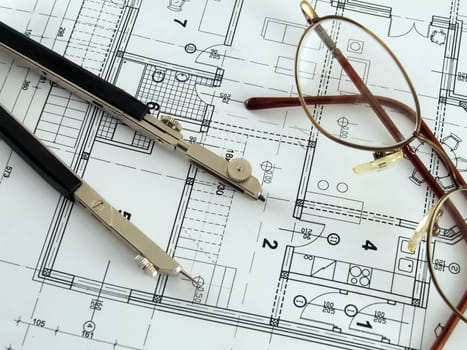 Divider and spectacles laying on architectural plan