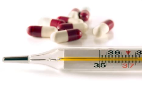 thermometer and pills over white background