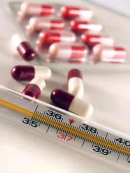 closeup of thermometer and pills