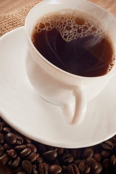 Cup of coffee with coffee beans around