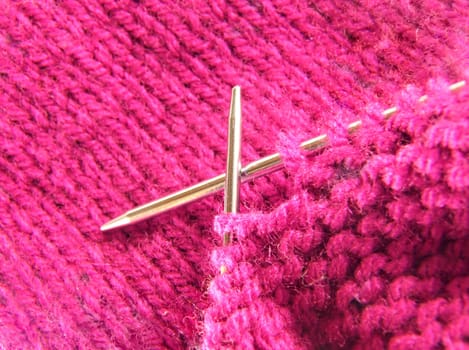 a pair of knitting needles and pink yarn