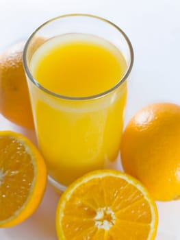 closeup orange juiceand few oranges on white