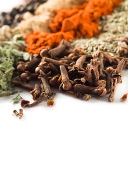 closeup of cloves and other spices over white
