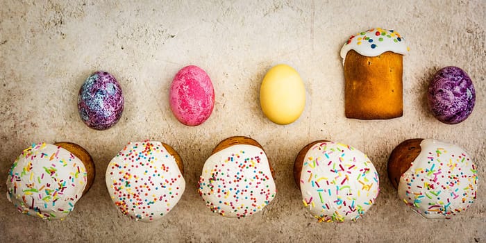 Easter cakes and Easter colored eggs on a beautiful textured background. Religious holiday of bright Easter.