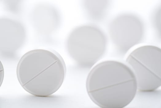 A pile of white pills scattered on a bright white background. Selective focus. Mockup layout, template.