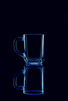 Just a glass on a black background with a reflection. Blue colors. Isolated.