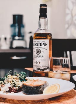 Salmon steak with a salad of herbs, spices and vegetables is served with whiskey. Supper. 07.02.2021. Samara, Russia.