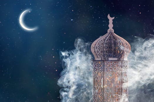 Ornamental Arabic lantern with crescent moon glowing at night. Festive greeting card for Muslim holy month Ramadan Kareem.