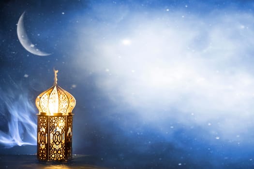 Ornamental Arabic lantern with crescent moon glowing at night. Festive greeting card for Muslim holy month Ramadan Kareem.