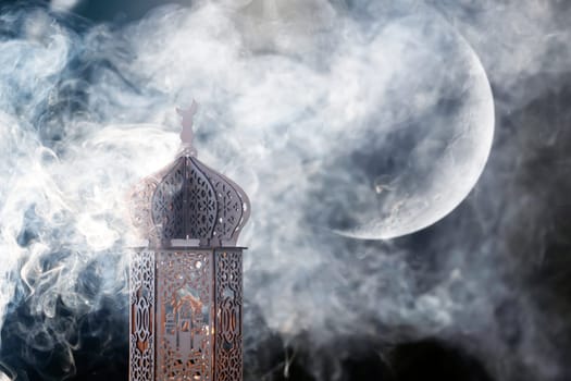 Ornamental Arabic lantern with crescent moon glowing at night. Festive greeting card for Muslim holy month Ramadan Kareem.