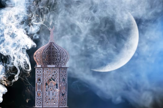 Ornamental Arabic lantern with crescent moon glowing at night. Festive greeting card for Muslim holy month Ramadan Kareem.