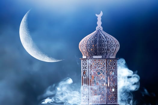 Ornamental Arabic lantern with crescent moon glowing at night. Festive greeting card for Muslim holy month Ramadan Kareem.