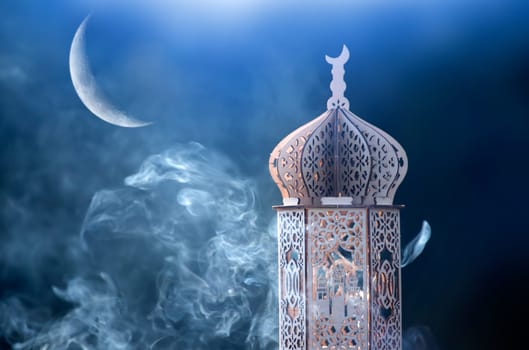 Ornamental Arabic lantern with crescent moon glowing at night. Festive greeting card for Muslim holy month Ramadan Kareem.