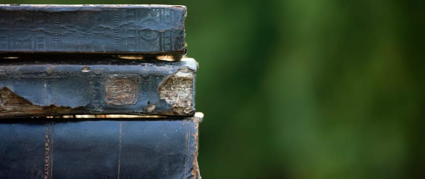 Literature, reading concept: banner or header image with stack of antique books against a dark background