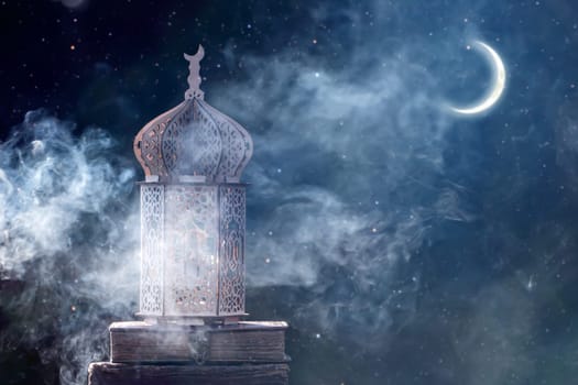 Ornamental Arabic lantern with crescent moon glowing at night. Festive greeting card for Muslim holy month Ramadan Kareem.
