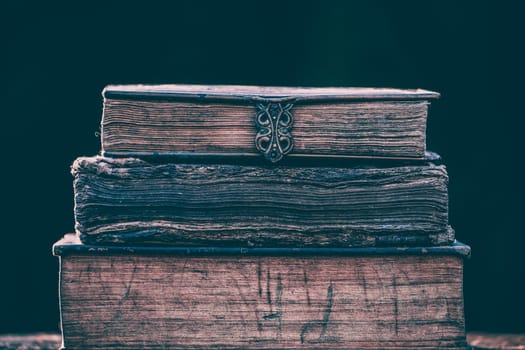 Literature, reading concept: banner or header image with stack of antique books against a dark background