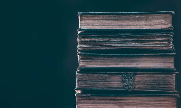 Literature, reading concept: banner or header image with stack of antique books against a dark background