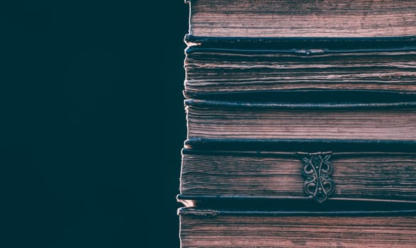 Literature, reading concept: banner or header image with stack of antique books against a dark background