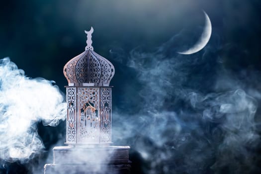 Ornamental Arabic lantern with crescent moon glowing at night. Festive greeting card for Muslim holy month Ramadan Kareem.