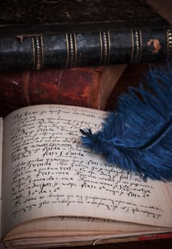 Feather, old books and manuscript on the table
