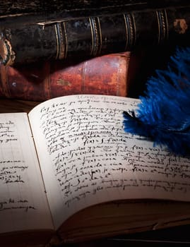 Feather, old books and manuscript on the table