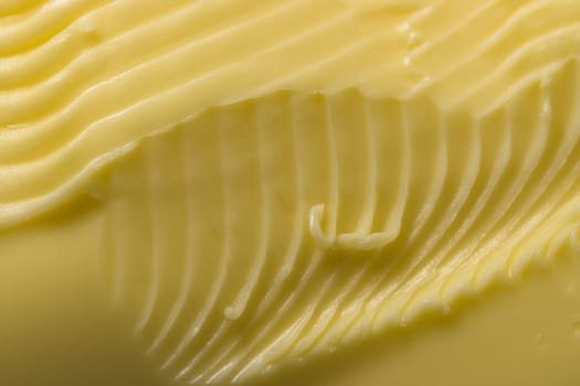 Super close up macro background of intricate grooves and swirls of margarine. Made by a serrated kitchen knife that was swept over the surface.
