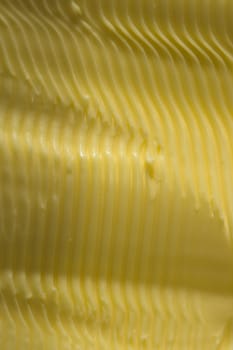 Vertical food texture image. Full frame margarine, textured into wavy ridges using a knife. Commonly found in kitchens as an alternative to butter