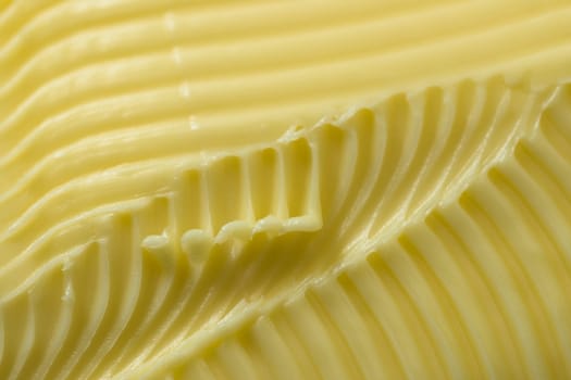 Close up of yellow butter. Full frame textured background, with a super macro perspective. Serrated butter knife used to create the abstract patterns
