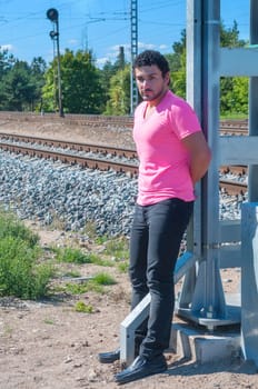 Handsome young guy in pink t-shirt watching on you.