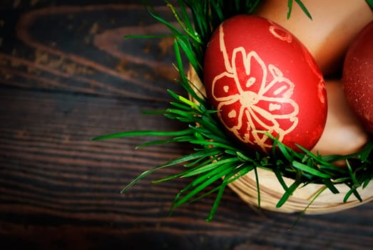 Red easter eggs in wooden basket with grass