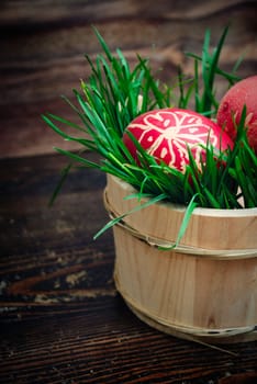 Red easter eggs in wooden basket with grass