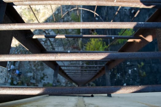 An old rusty staircase to the roof of the building. Abandoned industrial object.