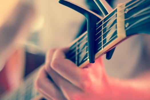 Young man playing a sunburst western guitar: cut out, blurry