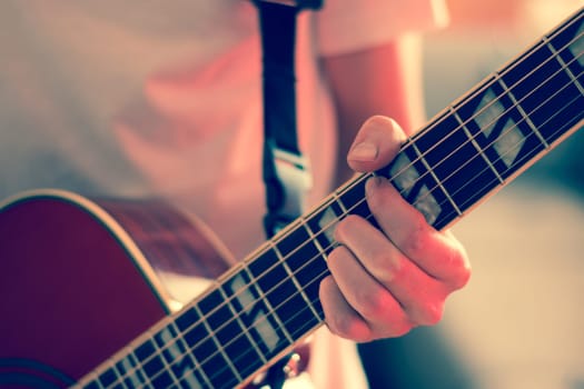 Young man playing a sunburst western guitar: cut out, blurry