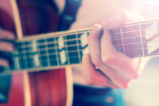 Young man playing a sunburst western guitar: cut out, blurry