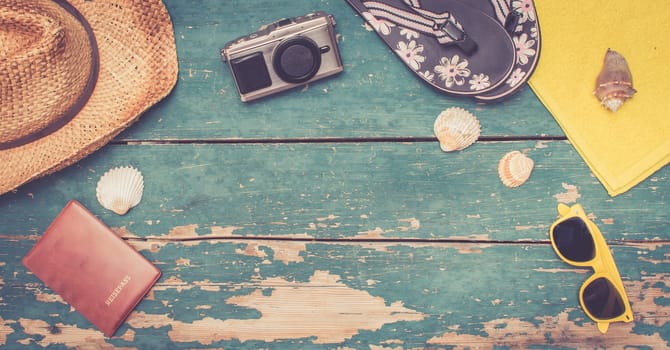 Summer background: Concept of leisure travel in the summer: Straw hat, sunglasses, shells, vintage camera, passport and flip flops. Copy space.