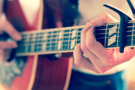Young man playing a sunburst western guitar: cut out, blurry