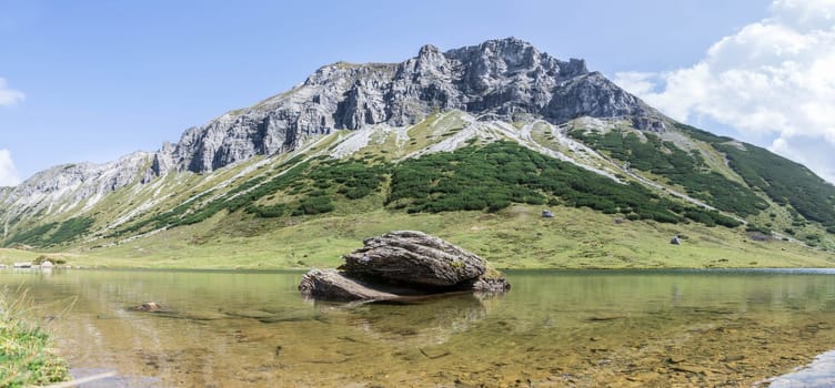 Lake with clear water in the foreground, rugged mountains in the background
