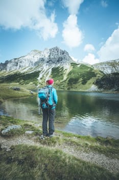 Female blonde mountain climber with backpack is enjoying the view