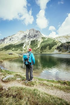 Female blonde mountain climber with backpack is enjoying the view