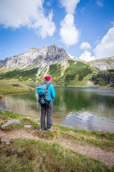 Female blonde mountain climber with backpack is enjoying the view