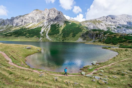 Mountain landscape: Rocky mountain range, clear water lake and blue cloudy sky