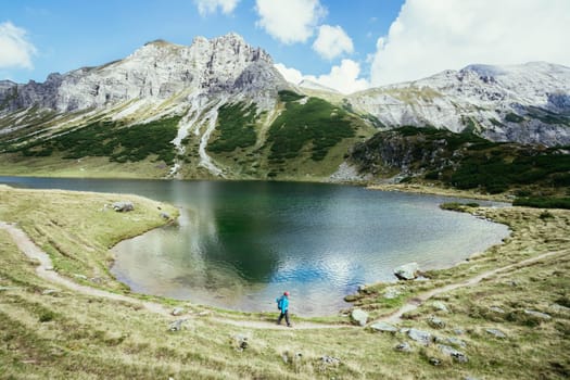 Mountain landscape: Rocky mountain range, clear water lake and blue cloudy sky