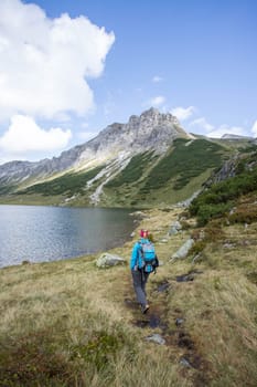 Mountain landscape: Rocky mountain range, clear water lake and blue cloudy sky