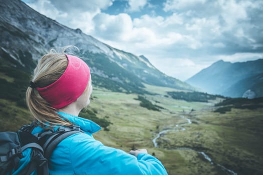 Woman in sportswear and with backpack enjoys the view in the mountains