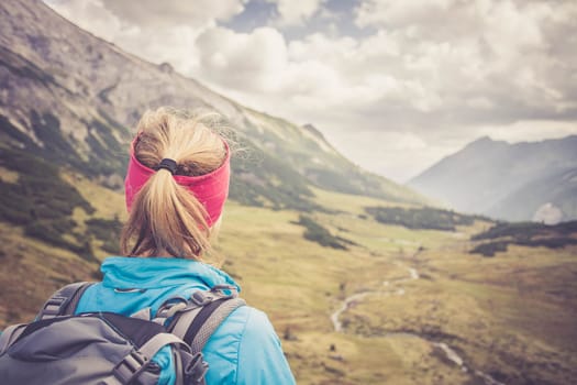 Woman in sportswear and with backpack enjoys the view in the mountains