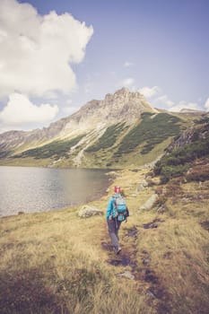 Mountain landscape: Rocky mountain range, clear water lake and blue cloudy sky